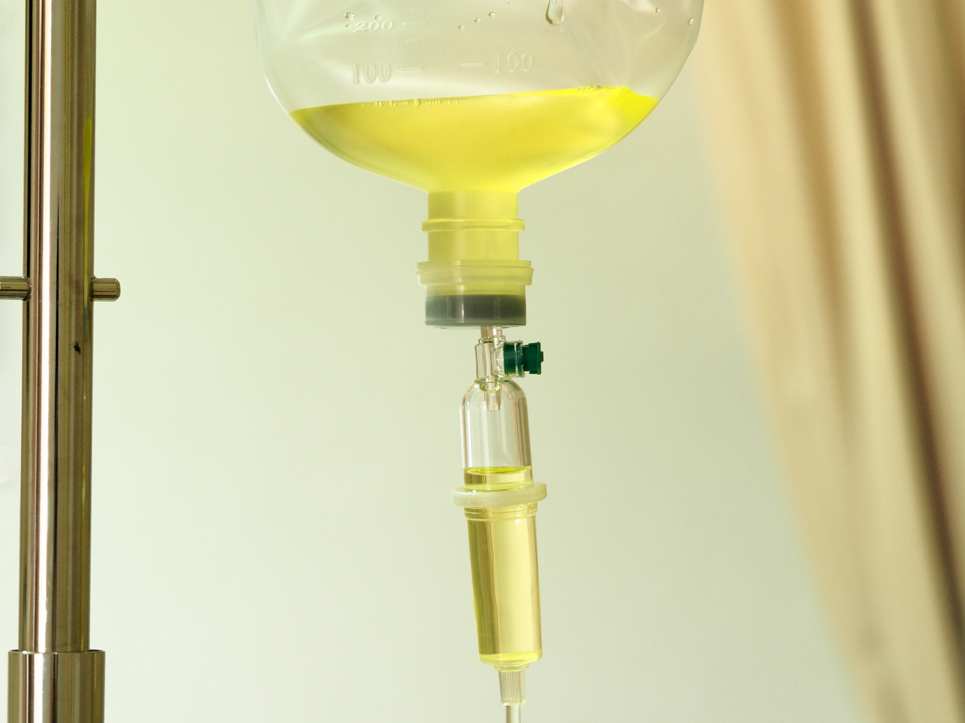Close up medical IV vitamin drip with tubing hanging on standing, vitamin therapy, medical concept